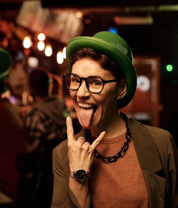 Woman joyfully moving to the music in a dark room with mint green light streaks.